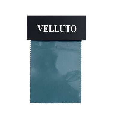 A sample of Velluto solid velvet fabric in blue color, displayed with a label at the top.